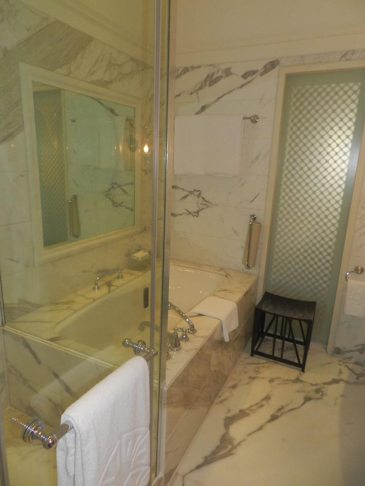 The Taj Mahal Tower, Mumbai Hotel Buitenkant foto The photo displays a bathroom featuring a luxurious design. There is a glass-enclosed shower area alongside a large bathtub. The walls are adorned with marble, giving a sophisticated look. A few white towels are neatly arranged, and there is a small 