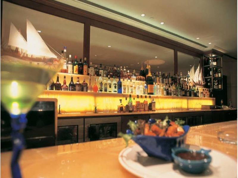The Taj Mahal Tower, Mumbai Hotel Buitenkant foto The photo depicts a stylish bar setting. In the background, there is a well-stocked bar shelf lined with numerous bottles of various alcoholic beverages, illuminated by soft lighting that creates a warm ambiance. The countertop appears to be smooth a