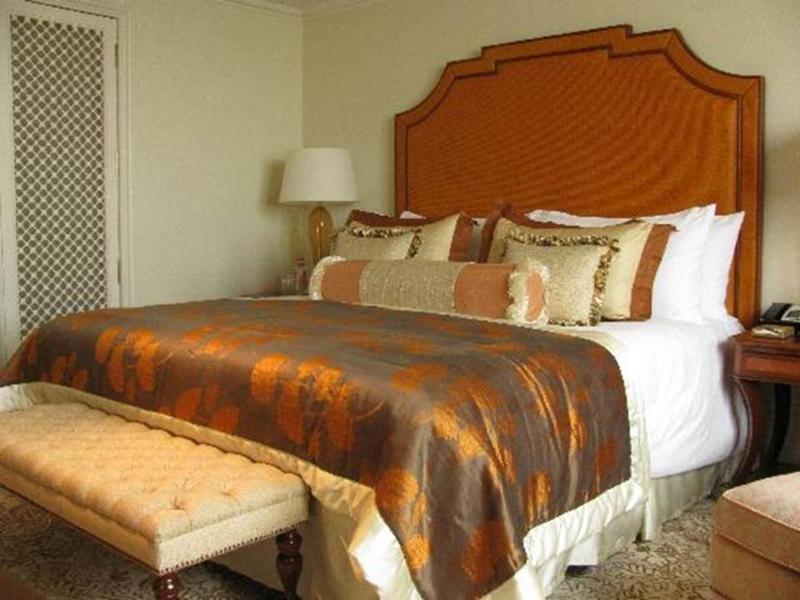 The Taj Mahal Tower, Mumbai Hotel Buitenkant foto The photo shows a well-decorated bedroom featuring a large bed with an ornate headboard. The bed is dressed with a luxurious comforter that has a blend of rich colors, including brown and gold accents, along with multiple decorative pillows. At the f
