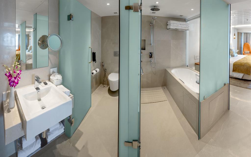 The Taj Mahal Tower, Mumbai Hotel Buitenkant foto The photo shows a modern bathroom with a sleek design. To the left, there is a sink with a mirror above it, and beneath the sink, there are some storage shelves. The area also features a glass partition leading to a shower. On the right side, there i